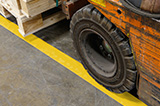 A forklift driving over ToughStripe Max Floor Tape.