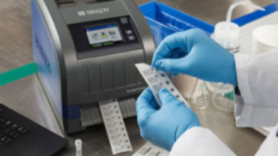 A person using a Brady printer to create custom labels for lab vials.