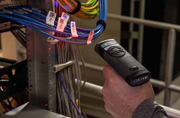 A worker at a server rack scans a qr code on a wrap around cable label using a barcode scanner.