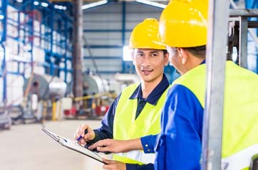 An inspector points to a checklist of safety hazards for a forklift driver.