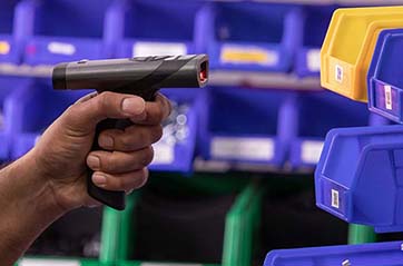A person in a warehouse scans a label with a programmable barcode scanner.
