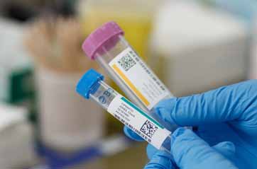 Two laboratory test tubes are labeled with a color coded label that includes a qr code.