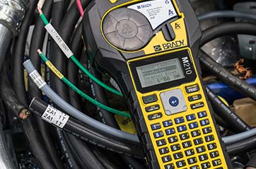 A Brady M210 label printer next to an array of labeled wires.