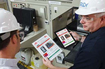 Workers discuss the LOTO procedures in an industrial setting.