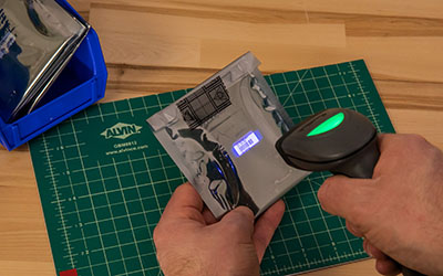 An employee scans a barcode label on the side of a product to check it into the inventory system.