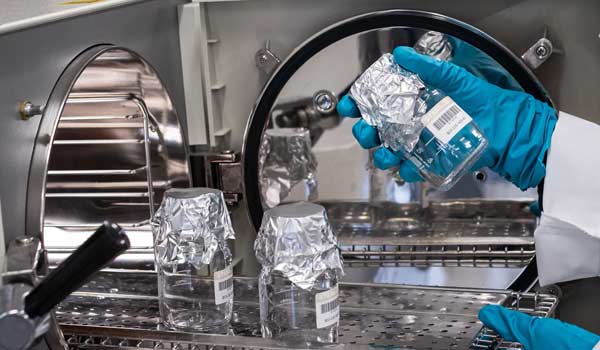 Sterilized containers with sterile labels are removed from an autoclave.