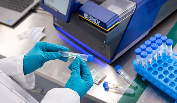 A Brady J7300 lab label printer is used to apply a custom barcode label to vials.