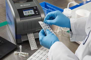 Scientist in a laboratory operating a Brady printer to create specimen labels.