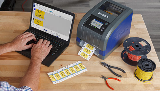 Overhead view of laptop, Brady printer, labels, spools of wire and pliers