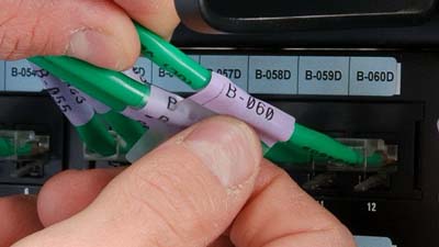 A person applies a self-laminating label to a wire.