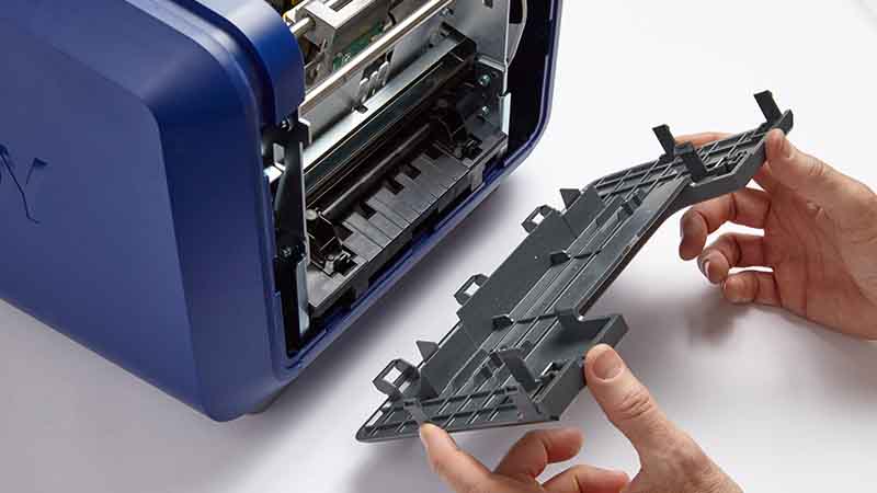 A person opens a panel on a printer to perform maintenance.