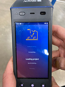 A hand holding a Brady HH83 RFID reader, poised for action as the Ignition app loads on the device's screen.